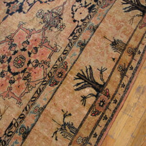 Low-pile rug featuring tan, black, and salmon traditional patterns bordered by distressed wood flooring.