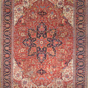 Red and navy traditional medallion rug with cream accents, featuring intricate vining designs on wood flooring.