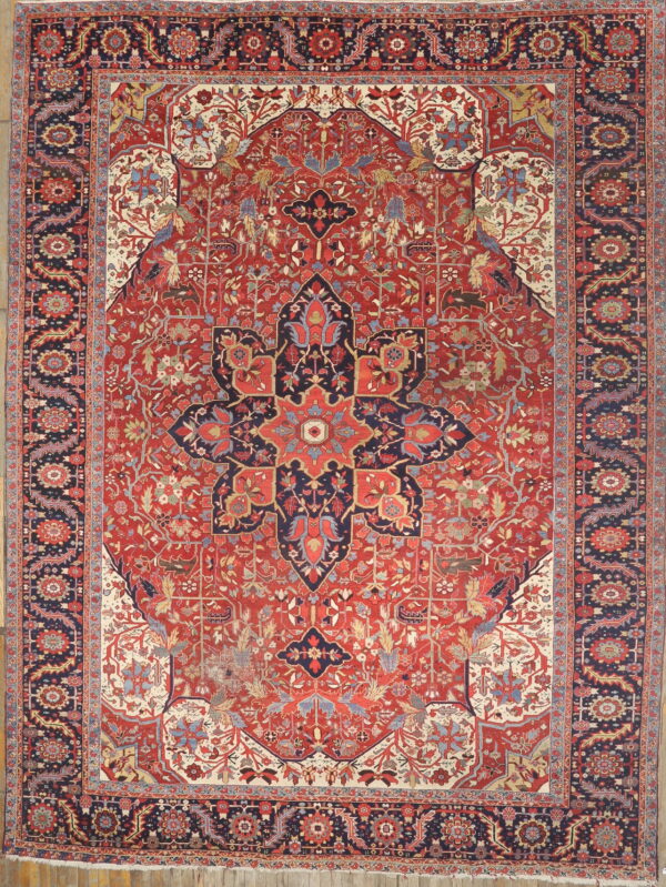 Red and navy traditional medallion rug with cream accents, featuring intricate vining designs on wood flooring.