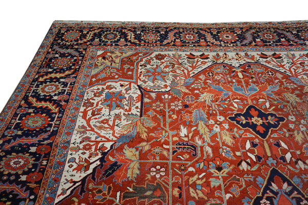 Detailed traditional rug featuring a rust red field with intricate blue, cream, and red floral motifs and borders.
