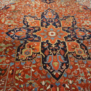 Ornate red rug with a central star-shaped navy blue medallion and complex floral vine patterns.