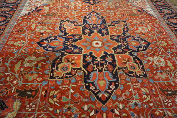 Ornate red rug with a central star-shaped navy blue medallion and complex floral vine patterns.