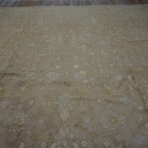 Beige distressed rug with a dense botanical pattern in cream, pale yellow, and light blue on wood floor.