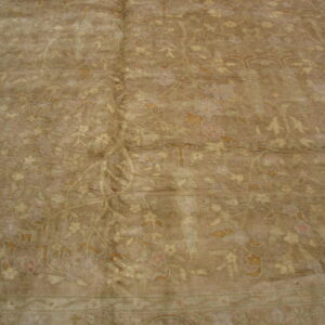 Low-pile rug in tan and brown shades featuring a faded floral and vine traditional design.