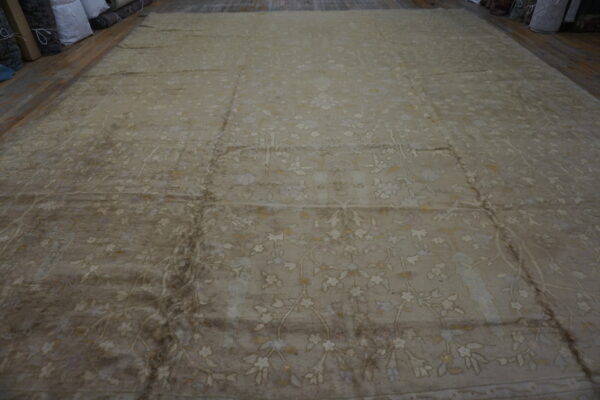 Expansive low-pile taupe rug displays a subtle cream floral pattern on wood plank flooring.