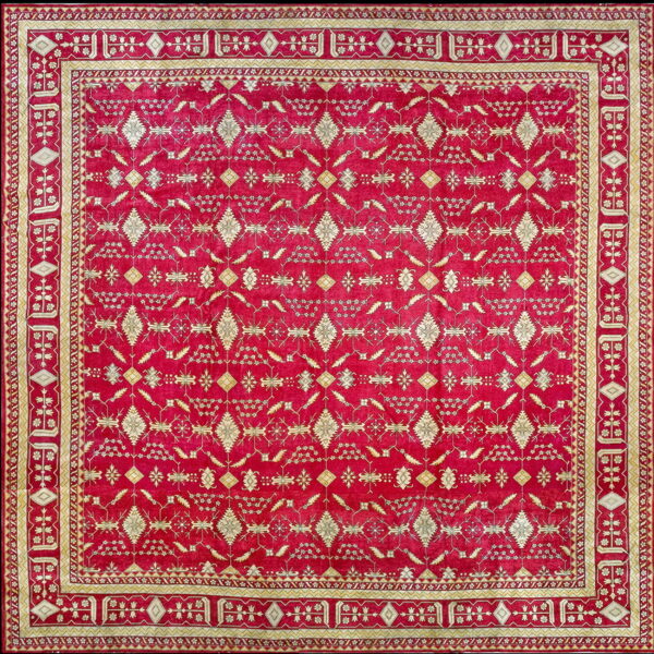 Square deep red rug with intricate cream and gold geometric patterns and multi-paneled borders.