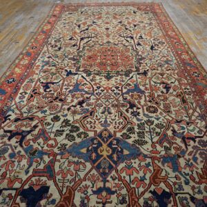 Low-pile area rug featuring an ornate medallion design in rust, navy, and cream on worn wooden floors.