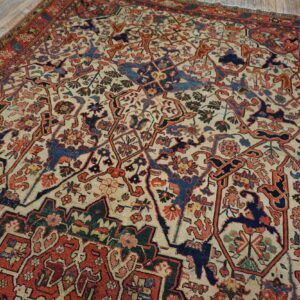 Detailed red, navy, and cream patterned rug with stylized designs lying on light wood floorboards.