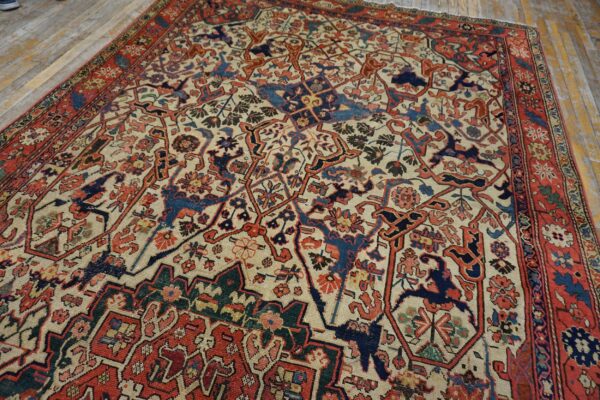 Detailed red, navy, and cream patterned rug with stylized designs lying on light wood floorboards.