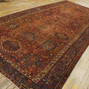 Large low-pile rug with complex red, navy, and tan geometric patterns displayed on light wood floor.