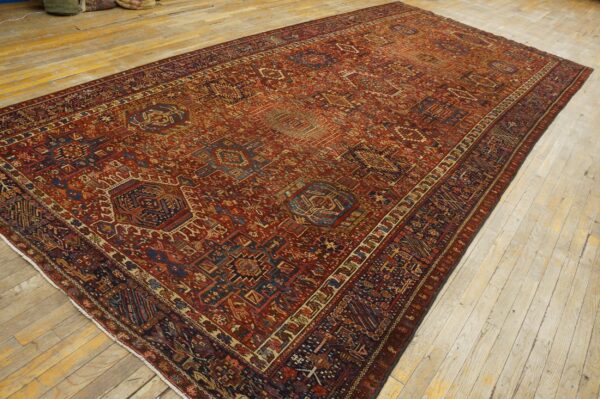 Large low-pile rug with complex red, navy, and tan geometric patterns displayed on light wood floor.