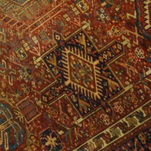 Geometric rug detail showing a deep red field patterned with navy blue, beige, and light blue motifs.