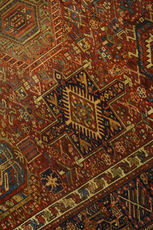 Geometric rug detail showing a deep red field patterned with navy blue, beige, and light blue motifs.