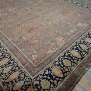 Ornate pink and blue rug featuring a dense floral pattern and wide paisley border on distressed wood floors.