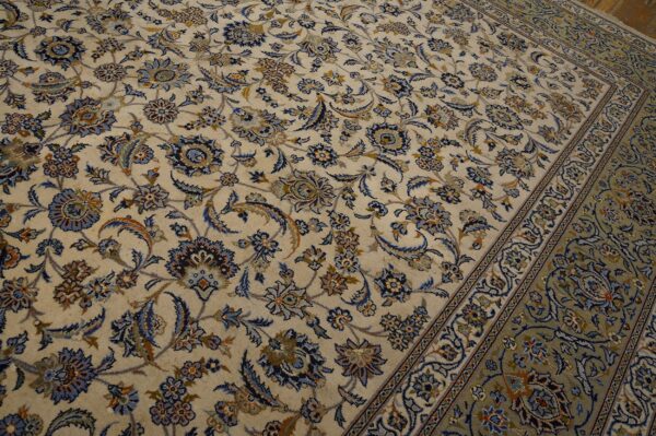 Cream rug with dense blue and gold floral motifs, transitioning to a patterned green border.