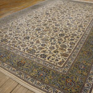 Cream rug featuring dense blue and tan floral motifs and a wide sage border on hardwood floors.