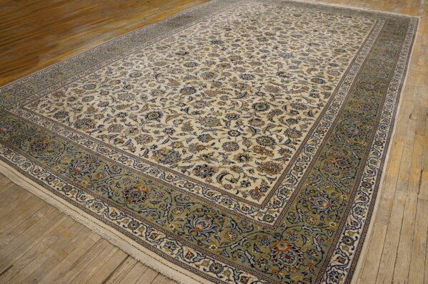Cream rug featuring dense blue and tan floral motifs and a wide sage border on hardwood floors.