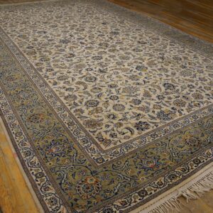 Cream and blue floral rug with a wide green border lying on distressed hardwood planks.