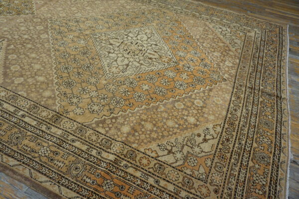Low-pile beige and tan medallion rug with complex floral patterns on weathered wooden floors.