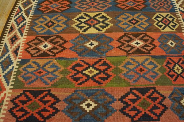 Multicolor flatweave rug displaying geometric medallions arranged in horizontal stripes on a wood floor.