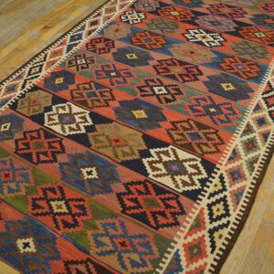 Geometric flatweave runner with red, blue, and earth-toned patterns resting on worn yellow wooden floorboards.