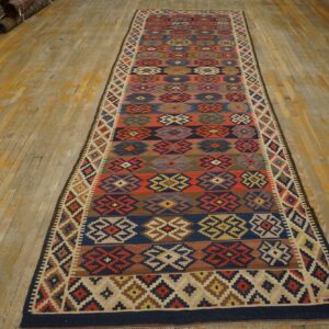 Flatweave multicolor runner rug with geometric patterns laid on distressed yellow wood floor.