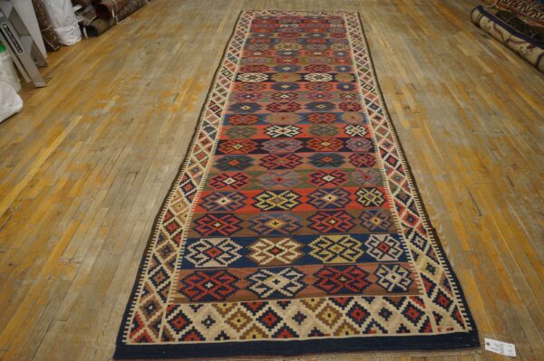 Flatweave multicolor runner rug with geometric patterns laid on distressed yellow wood floor.
