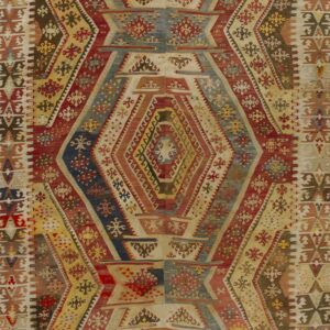 Colorful geometric flatweave rug with repeating vertical diamond medallions in red, yellow, blue, and beige.