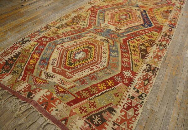 Geometric low-pile rug with central hexagons in red, yellow, and blue on rustic hardwood flooring.