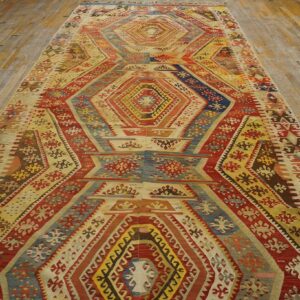 Multicolor geometric flatweave runner in shades of red, gold, and navy, displayed on aged wood planks.