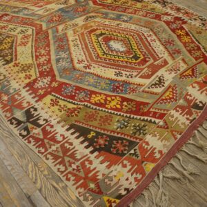 Geometric flatweave rug featuring a large medallion in vivid red, yellow, and blue on distressed wood planks.