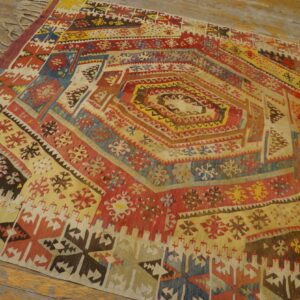Geometric flatweave rug featuring a central concentric design of red, yellow, and blue laid on wood flooring.