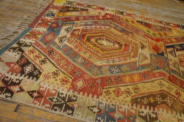 Geometric flatweave rug featuring a central concentric design of red, yellow, and blue laid on wood flooring.