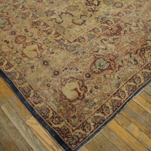 Detail of a traditional patterned rug featuring tan, burgundy, and navy colors on distressed wood planks.