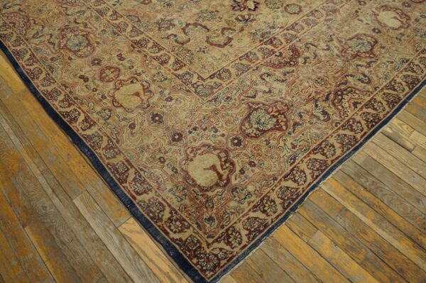 Detail of a traditional patterned rug featuring tan, burgundy, and navy colors on distressed wood planks.