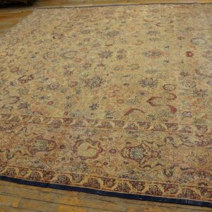 A large traditional rug with faded gold, red, and blue floral patterns rests on distressed wood flooring.