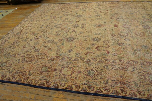 A large traditional rug with faded gold, red, and blue floral patterns rests on distressed wood flooring.