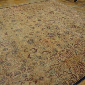 Distressed, low-pile rug with beige and faded burgundy floral motifs lying on rustic wooden planks.