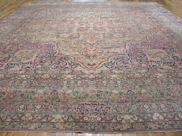 Low-pile rug with complex floral motifs in muted rose, beige, and indigo on a wood floor.