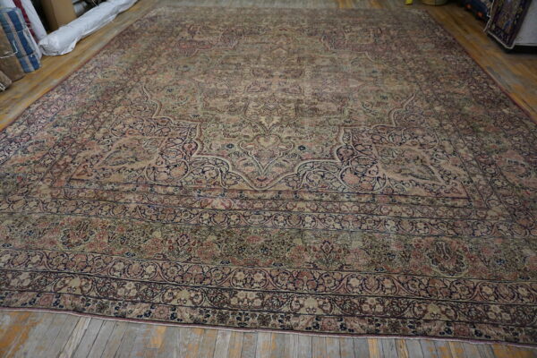 Traditional low-pile rug in beige, pink, and indigo with a central medallion on distressed wood flooring.
