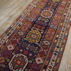 Geometric runner rug with a navy field and multicolored medallions resting on light weathered wood floorboards.