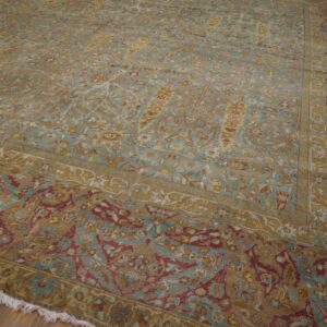 Large, traditional rug in teal, gold, and cranberry floral patterns resting on wooden floors.