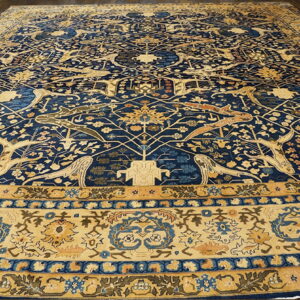 Navy blue and gold rug featuring stylized animals and intricate floral patterns on a dark wood floor.