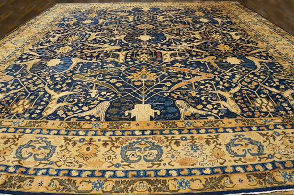 Navy blue and gold rug featuring stylized animals and intricate floral patterns on a dark wood floor.