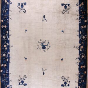 Cream rug with scattered blue floral designs and a wide navy border of pink and blue flowers on wood floor.