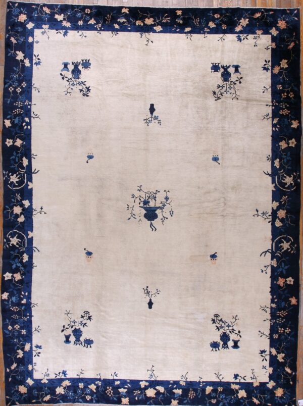 Cream rug with scattered blue floral designs and a wide navy border of pink and blue flowers on wood floor.