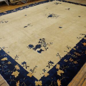 Large cream rug with a navy blue border featuring light floral patterns lies on wood floors.