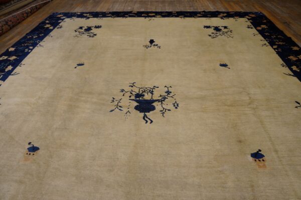 Large beige rug with dark blue stylized floral patterns and a wide navy border on wood flooring.