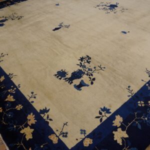 Cream rug with scattered blue floral patterns and a dark blue border featuring tan blossoms on wood planks.