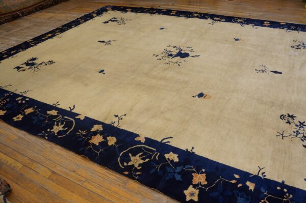The light tan rug features a dark blue border with orange and blue floral motifs on wood flooring.